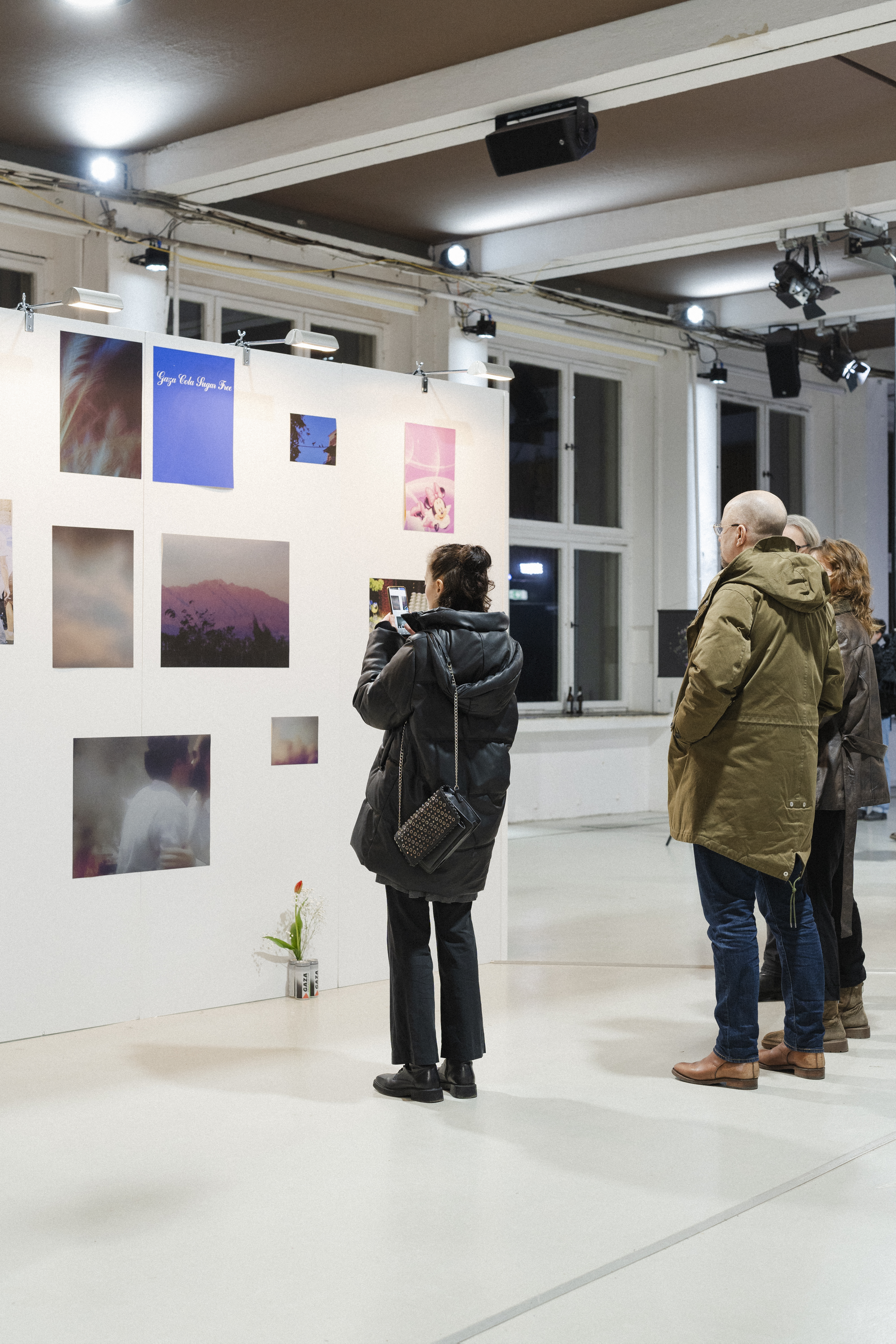 The picture shows the exhibition view of the first tour of the Jewish Art School. Visitors view photographs of various formats on a white gallery wall in modern exhibition rooms.