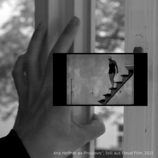 Das schwarzweiße Filmstandbild von Ana Hoffner ex-Prvulovic* zeigt eine Hand und einen Bildschirm mit Treppe hinabsteigender Person.