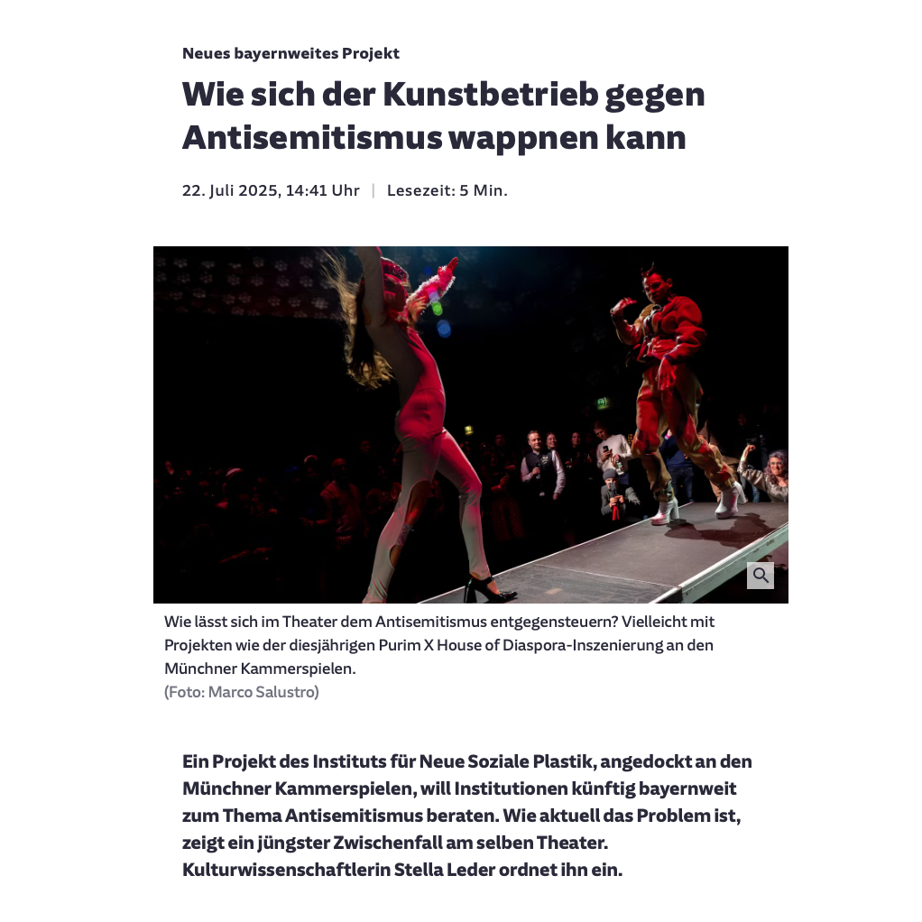Zwei Personen in Kostümen schreiten auf einem Laufsteg aufeinander zu. Im Hintergrund befinden sich Publikumspersonen, die sie fotografieren.