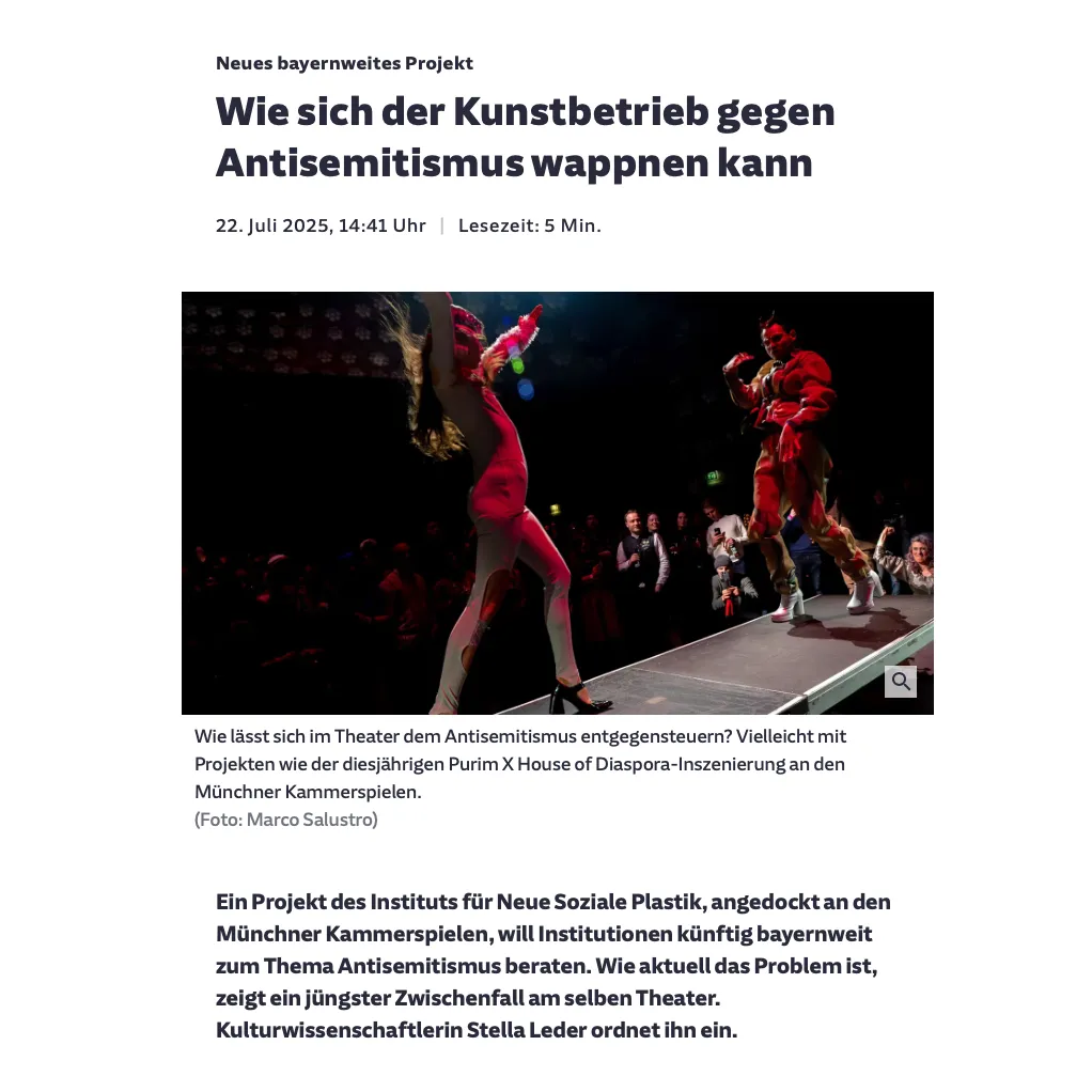 Zwei Personen in Kostümen schreiten auf einem Laufsteg aufeinander zu. Im Hintergrund befinden sich Publikumspersonen, die sie fotografieren.